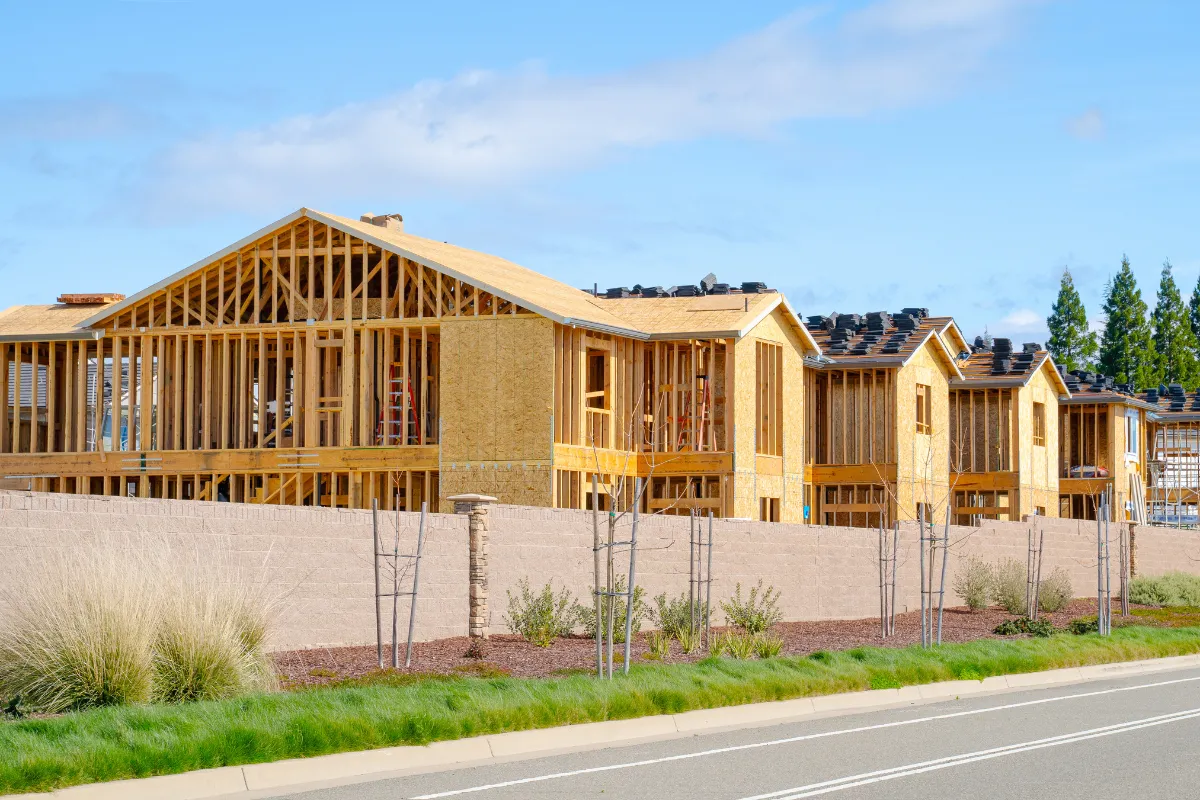 New home construction in Los Angeles with multiple residential homes framed under construction behind a block wall