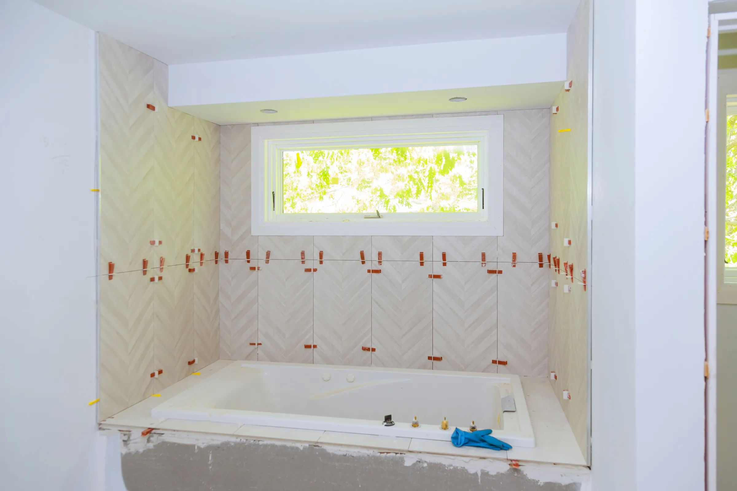 Bathroom remodeling in Los Angeles with bathtub installation, marble-look wall tile, waterproofing prep, and renovation work in progress